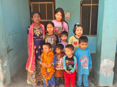 Children of Sahara Ghar gathered outside the shelter, one wearing a marigold garland
