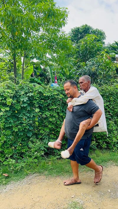 Bal Bahadur Bista carrying an elderly resident to safety