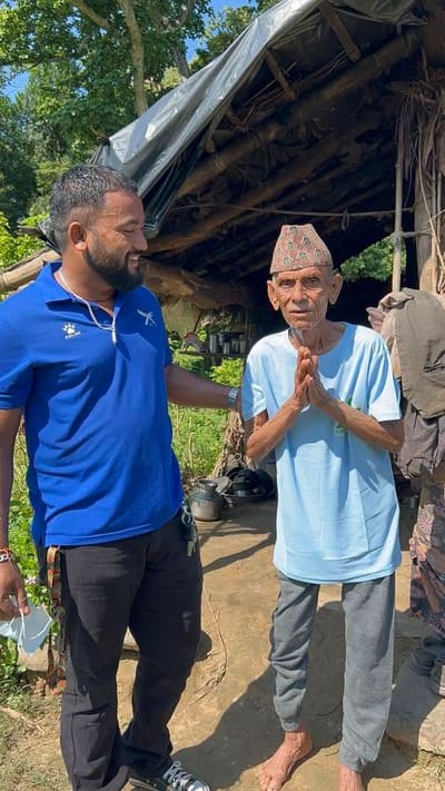 A caregiver with a hand on the shoulder of an elder greeting him outside a makeshift shelter